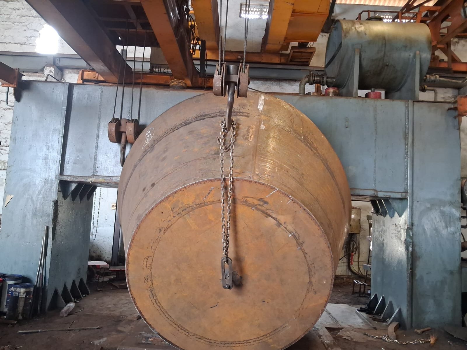 Large conical dished end suspended by overhead crane during hydraulic pressing